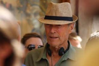 Clint Eastwood durante la lavorazione di un film con cappello e cuffie intorno al collo