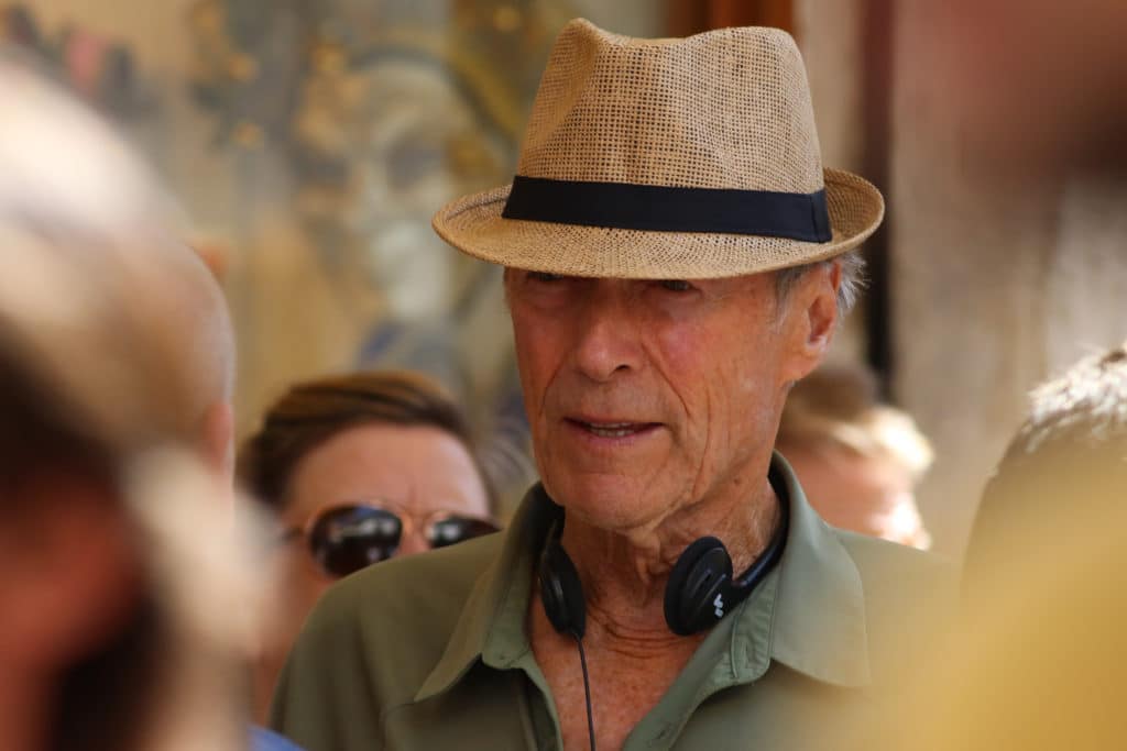 Clint Eastwood durante la lavorazione di un film con cappello e cuffie intorno al collo