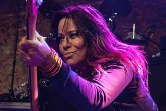 Jennifer Finch sul palco con il basso durante un concerto della rock band L7